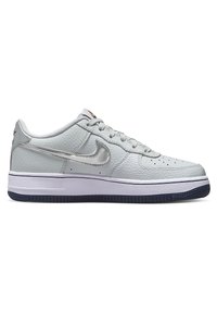 Baskets basses en cuir gris clair avec virgule Nike argent métallisé, semelle intermédiaire blanche et semelle extérieure noire, vues de profil.