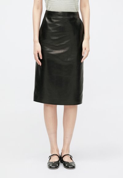 Black leather skirt with a straight design, featuring a high waist and smooth texture. Worn with black shoes, set against a white background.