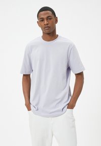 Lyslilla kortærmet T-shirt lavet af blødt bomuldsstof. Rund halsudskæring og afslappet pasform med subtile syninger og uden synlige mønstre.