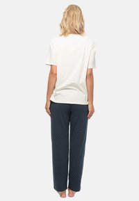 T-shirt en coton blanc associé à un pantalon de pyjama bleu marine à pois. Le pantalon présente une coupe ample et une taille élastique.