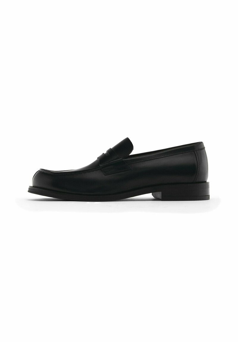 Schwarze Leder-Schlüpfschuhe mit runder Zehenform, ausgestattet mit einer dekorativen Fransenapplikation, flachem Absatz und dezenten Nähdetails entlang der Kanten.