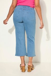 Ljusblå cropped denimjeans med medelhög midja, med två bakfickor och rak benöppning. Bärs tillsammans med bruna klacksandaler.