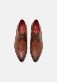 Scarpe derby in pelle marrone con dettagli brogue intricati, punta appuntita e lacci scuri. Fodera interna rossa con logo del marchio visibile.