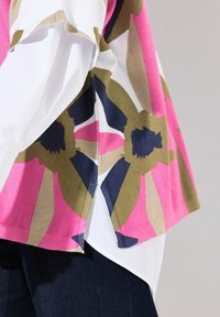 Gemusterte Bluse mit kräftigen Pink-, Grün- und Marineblau-Tönen auf einem weißen Stoffgrund. Sie verfügt über ein gespaltenes Hemd-Design für zusätzlichen visuellen Reiz.