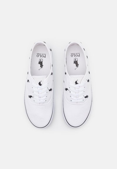 Sapatilhas de lona brancas com logos de jogador de polo pretos, bico redondo, atacadores brancos e sola preta contrastante. Etiqueta interior exibe "Polo Ralph Lauren."