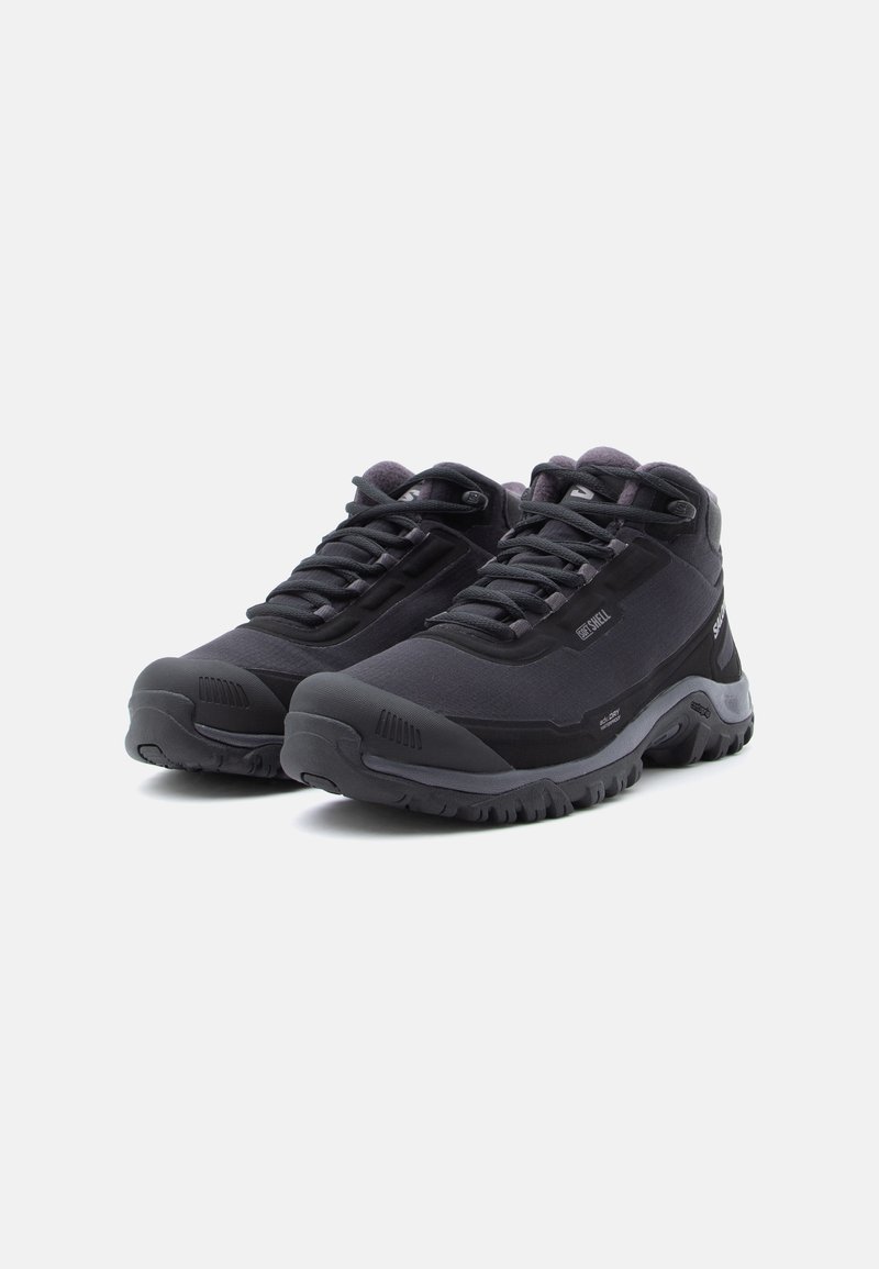Schwarze Wanderschuhe mit hohem Design, synthetischem Obermaterial, Gummisohle und strukturierten Akzenten. Verfügt über Schnürung und verstärkten Zehenbereich.
