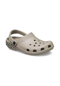 Beige Clogs mit einem perforierten Obermaterial, strukturiertem Riemen und ausgeprägten Spitzen auf der Rückseite. Flexibles Material und ein Riemen an der Rückseite für einen sicheren Sitz.