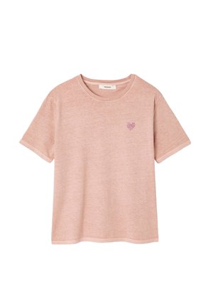 T-shirt rose clair à manches courtes en coton doux. Présente un petit motif de cœurs dans un rose légèrement plus foncé sur la zone gauche de la poitrine.