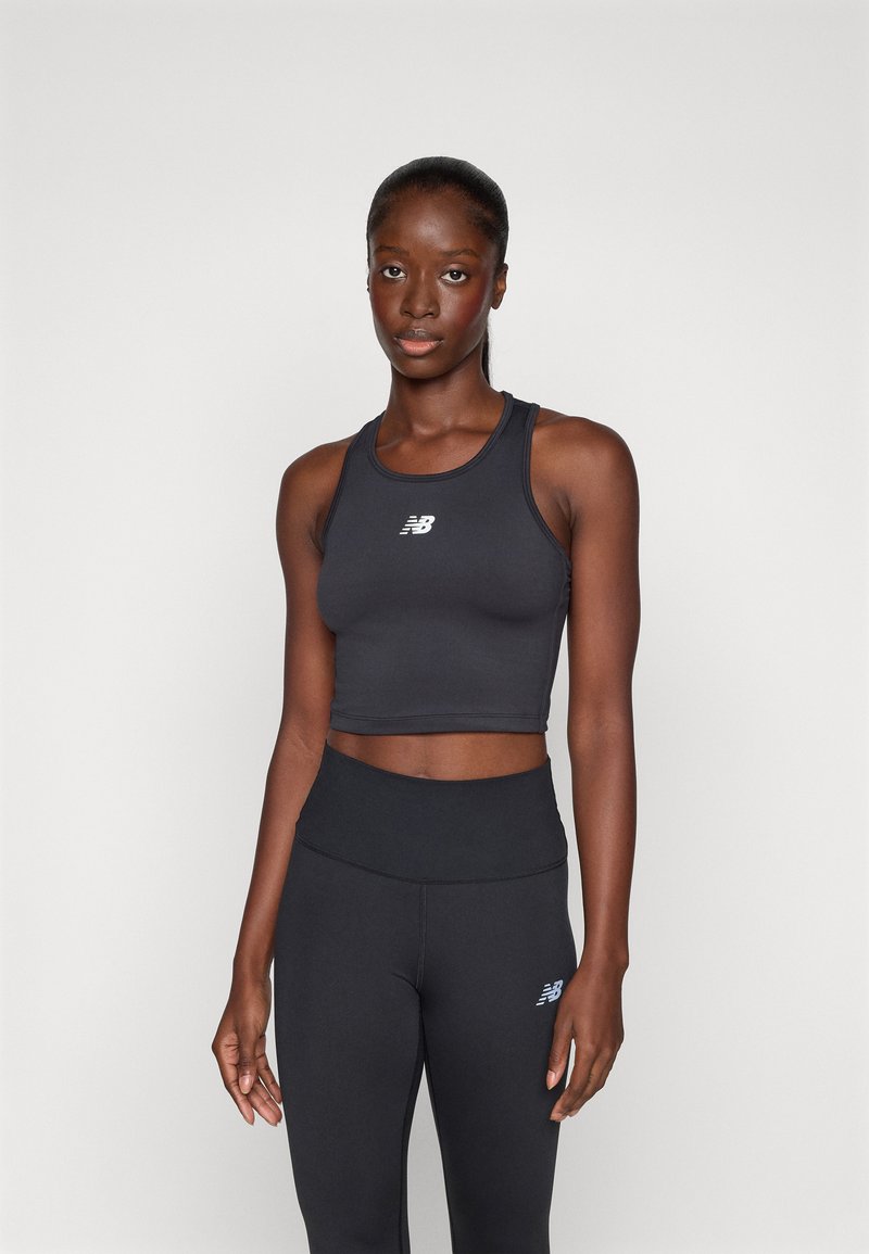 Top corto sportivo nero con design a schiena scoperta e piccolo logo bianco; abbinato a leggings neri a vita alta con logo abbinato.