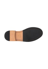 Musta kumipohja, jossa on sileä pinta, pyöristetty kantapää ja kontrastivärinen vaaleanruskea nahkapatchi. Reunoja koristaa beige ommel.