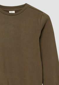 Brązowa bluzka z długim rękawem typu crewneck z prążkowanym kołnierzem, widocznymi szwami na ramionach oraz metką wewnątrz dekoltu na jasnym tle.