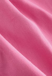Rosa bomullstyg med en slät textur, som visar en diagonalfold som avslöjar vävningens mönster och en jämn färg genom hela tyget.