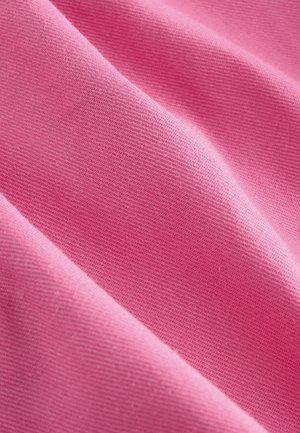 Vaaleanpunainen puuvillakangas, jossa on sileä pinta, ja joka näyttää vinoon taitoksen, joka paljastaa kudontakuosin ja tasaisen värityksen koko pinnalla.