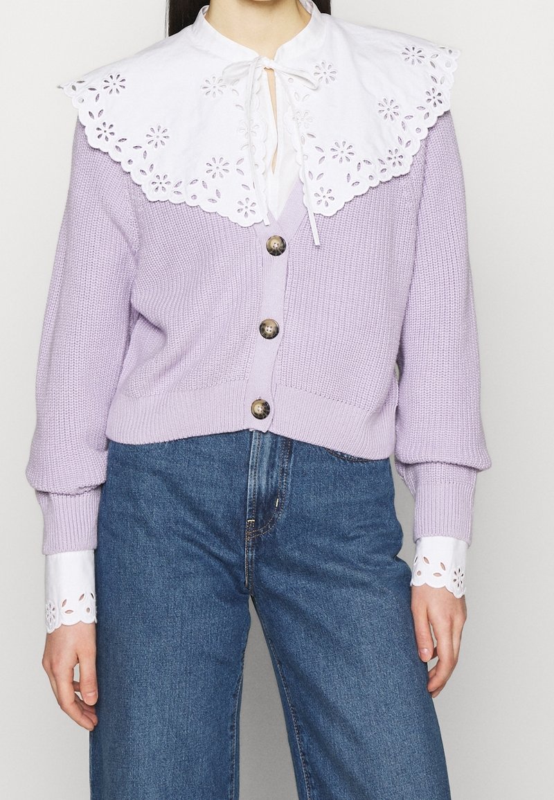 Lavendelstickad cardigan med en vit broderad krage med blommönster, tre knappar och ribbade ärmslut med spetsdetaljer.