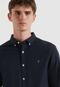 Camicia blu navy button-up in tessuto di cotone con colletto casual, caratterizzata da un sottile logo "F" ricamato arancione e bottoni argentati.