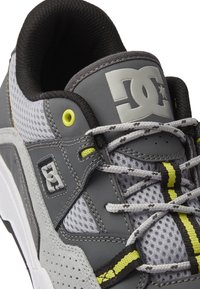 Scarpa da ginnastica grigia realizzata in mesh e suede, con dettagli gialli, lacci multicolori e suola in gomma con finiture texture.