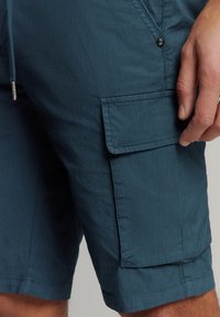 Teal cargoshorts van een lichtgewicht stof, met een zijzak, een trekkoord in de taille en gestikte details langs de naden.