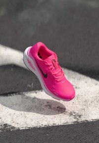 Rosa Nike Laufschuh, oberer Teil aus synthetischem Mesh, gepolsterte Sohle, schwarzes Logo und Akzente, leicht, strukturierte Oberfläche, leicht erhobener Absatz.
