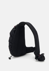 Sac à épaule noir avec une texture matelassée, une sangle en maille rembourrée et un cordon réglable. Comprend une fermeture éclair sécurisée et des accents en métal.