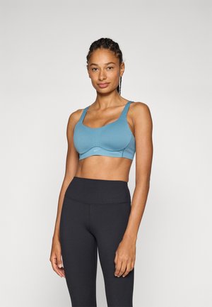 Top desportivo azul claro com alças largas e design sem costuras. O material é suave e elástico, com uma marcação mínima na parte da frente.