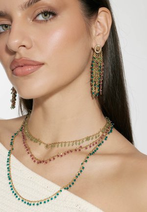 Goldfarbene Kettenjewelry mit geschichteten Halsketten, die mehrfarbige Perlen (grün, blau, pink) enthalten, sowie passenden, hängenden Ohrringen.