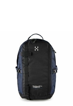Zaino compatto nero e blu navy con cerniera, cinghie laterali, anelli frontali e marchio "TIGHT SMALL" sul pannello frontale.