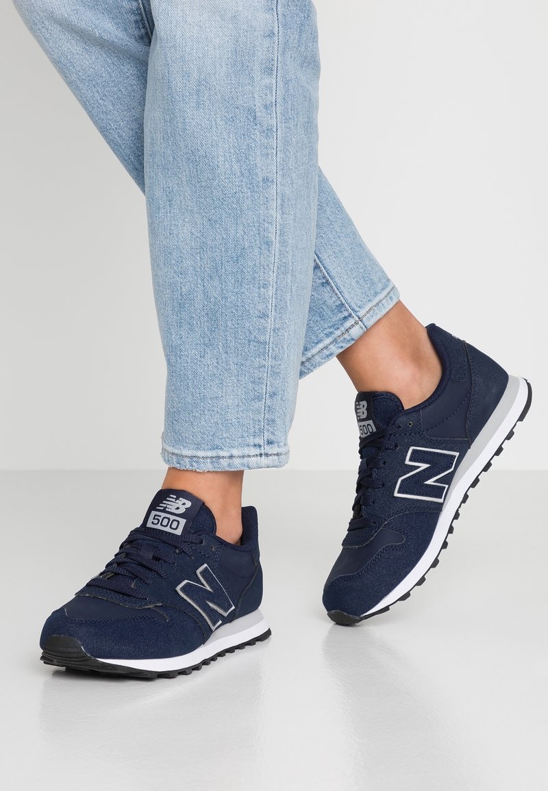 Námořnické modré tenisky New Balance 500 vyrobené z textilu a gumy, s bílým logem, černou podrážkou a zaobleným špičkovým designem.