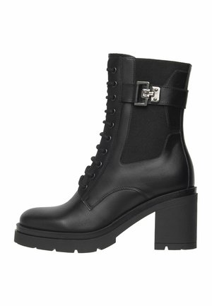 Bottes pour la cheville en cuir noir avec un talon rectangulaire, semelle crantée, devant à lacets, panneau latéral élastique et sangle décorative en argent avec boucle.