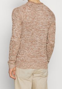 Texturerad stickad tröja i rost- och krämtoner med rund halsringning och åtsittande manschetter, med en ribbad fåll för en snug passform.