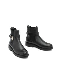 Botas de tobillo de piel negra con acabado texturizado, con una correa lateral y hebilla, punta redondeada y tacón bajo.