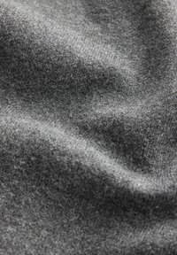 Sivé tkanivo s jemným, textúrovaným povrchom. Materiál vykazuje jemné odtiene farby a hĺbky, čo vytvára zvlnený vzhľad.