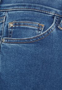 Jeans i denim med en djupblå färg, standard design på bakfickorna, kontrasterande beigt sömnad och detaljer i silver.