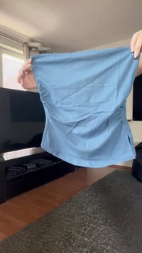 Hände halten eine hellblaue Stoffwindel oder waschbare Trainingshosen in einem Wohnzimmer mit Fernseher und Teppichboden.