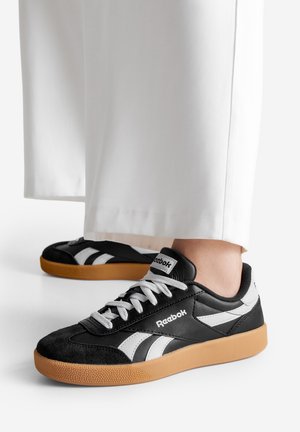 Černobílé nízké sportovní boty se svrškem z semiše a kůže, bílé šněrování a gumovou podrážkou, s logem na jazyku.