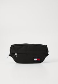 Zwarte stoffen pouch met een ritssluiting, voorzien van een voorvak en een klein multikleurig "TOMMY JEANS" logo patch. Compact en duurzaam ontwerp.