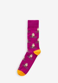 Lys pink sok med gul tå, med et gentaget design af tegneserie pindsvin, der står på ski på grønne ski. Blødt stof, mellemlang længde.