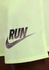 Pantalones cortos de running verde lima con un gráfico negro de "RUN" y un swoosh de Nike. Hechos de un tejido ligero y transpirable con un panel lateral de malla texturizada.