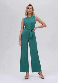 Macacão verde-água com pernas largas, design sem mangas e cintura atada. Tecido suave e leve, apresentando uma silhueta limpa e minimalista.