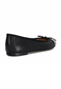 Black leather ballet flat with a rounded toe, minimalistic design, thin black trim, and a small bow accent on the front. Flat sole.