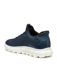 Baskets bleu marine avec une tige en mesh texturé, des accents en cuir lisse et une semelle extérieure ondulée blanche. Équipées d'une languette à l'arrière pour un enfilage facile.