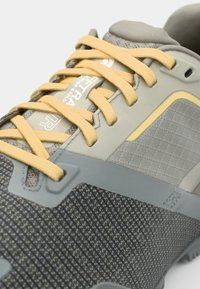 Gray hiking shoe featuring a textured mesh upper, yellow laces, and a reinforced rubber sole. Includes logo on the tongue and patterned details.