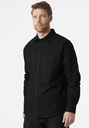 Camisa negra de botones con mangas largas, un bolsillo en el pecho y botones a juego. Fabricada con un tejido sólido y suave, con detalles de costura mínimos.