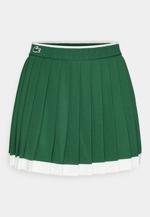 Green pleated skirt with a textured waistband. Features white accents at the hem and a small brand logo on the waistband.