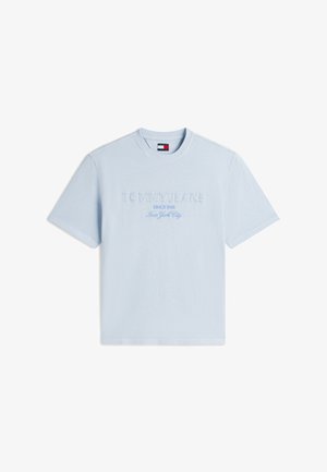Gai zils īsroku T-krekls ar uzrakstiem "TOMMY JEANS," "SINCE 1986" un "New York City" izšūti priekšpusē baltā un zilā krāsā.