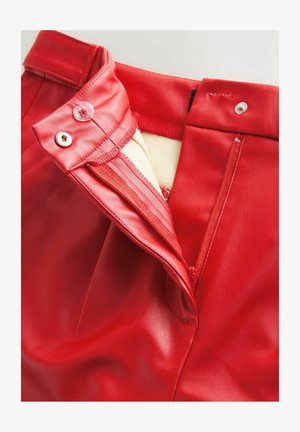 Pantaloni roșii din piele ecologică cu nasture vizibil, închidere cu fermoar și textură netedă. Prezintă o căptușeală interioară de culoare contrastantă.