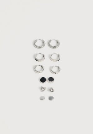 Six paires de boucles d'oreilles en argent dans différents styles : créoles striées, créoles lisses, petites créoles, clous ronds noirs, clous noués et clous plats.