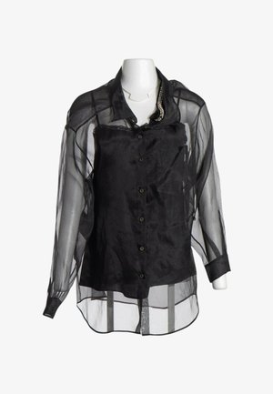 Schwarze transparente Langarmbluse mit Knopfleiste vorne und einfarbig schwarzem Untertop darunter auf einer weißen Schaufensterpuppe.