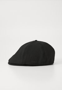 Black flat cap made of fabric with a smooth texture. Features a stitched front panel and a small metallic label on the side.