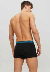 Schwarze Baumwoll-Boxershorts mit einem blauen elastischen Bund, der mit "JACK & JONES" Branding versehen ist. Das Design ist enganliegend und hat eine Länge bis zur Mitte des Oberschenkels.