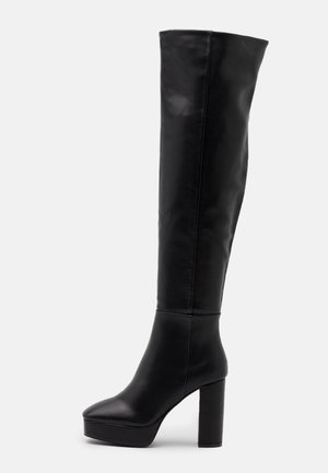 Bottes noires à talons hauts montantes au-dessus du genou en cuir lisse avec un talon bloc et un design à bout arrondi, présentant une tige sans couture et une plateforme.